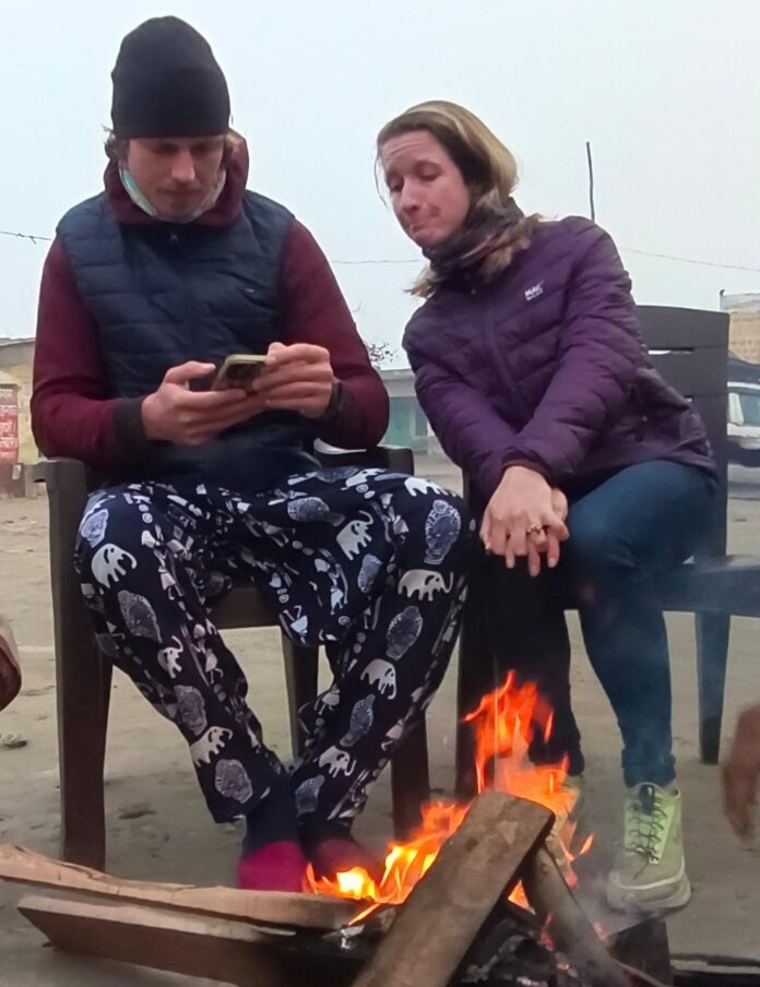 Foreign tourists removing cold by sitting in front of bonfire in Brajghat